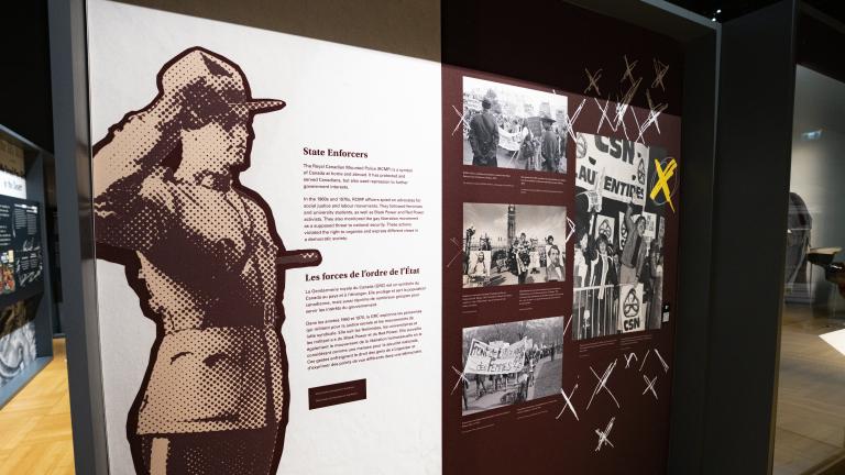 Exhibition panel with an image of an RCMP officer standing at attention and text that read "State Enforcers." Partially obscured.