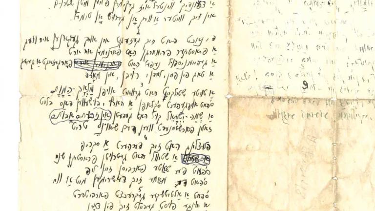 A yellowed paper with a handwritten text in Yiddish. The piece of paper is flat but was folded previously as old fold marks are obvious. Partially obscured.