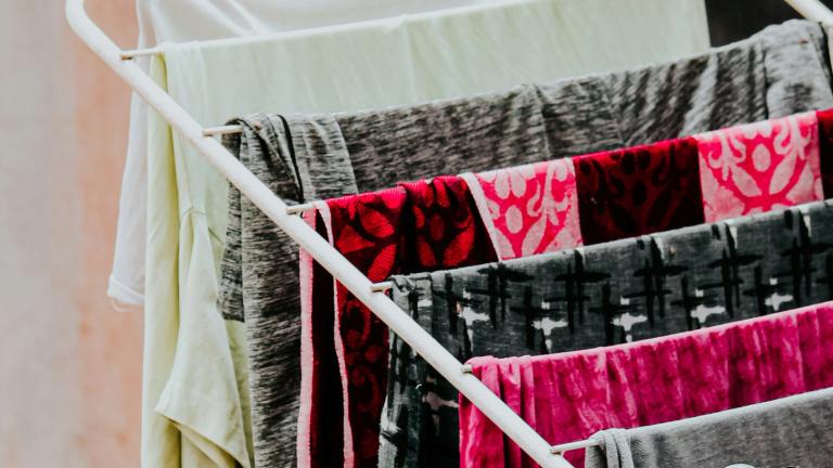 Garments are hung over a rack to air dry. The fabrics are grey, black, white and shocking pink. Partially obscured.