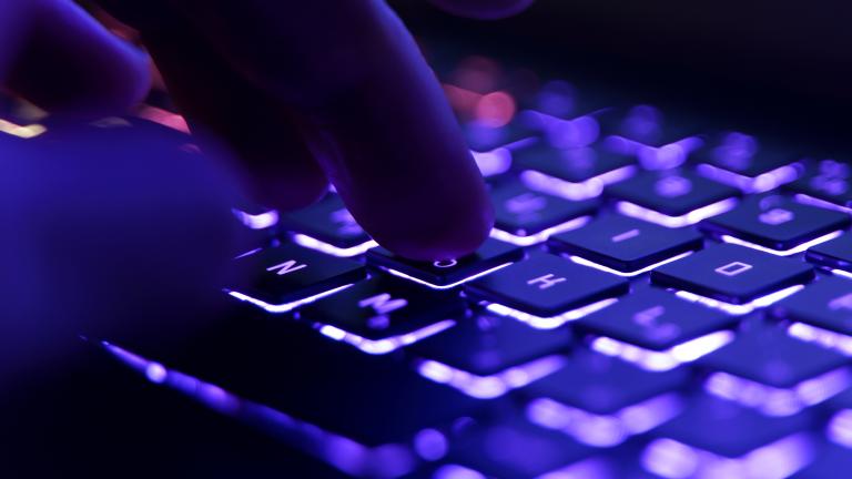 A hand hovers over a computer keyboard, ready to strike. Partially obscured.