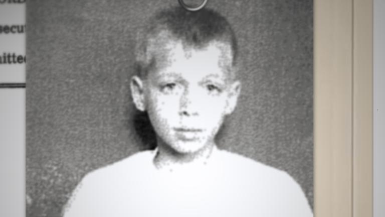 A black-and-white photo of a sad-looking boy is paperclipped to an institution admission form that asks his name, when he was admitted, and his mental condition. Partially obscured.