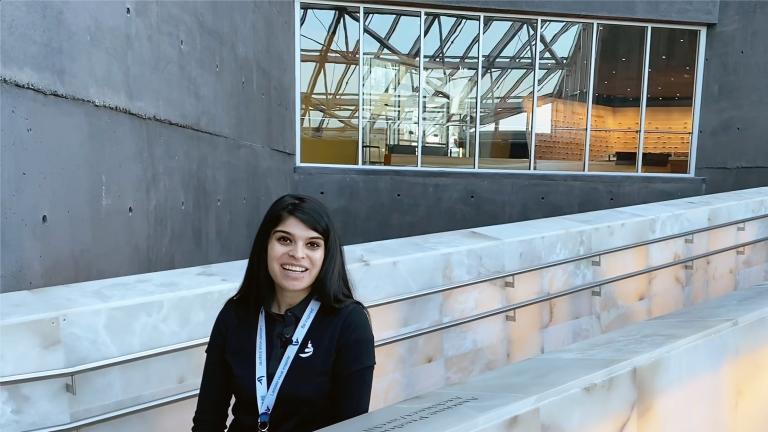 A smiling woman on the alabaster ramps of the Museum. Partially obscured.