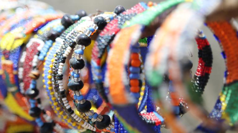 A display of colourful beaded bracelets are displayed for sale. Partially obscured.