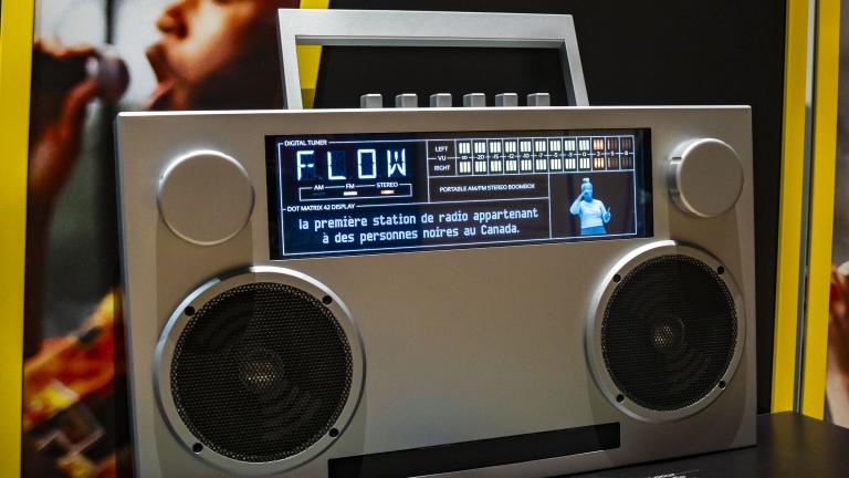Large boombox-style radio with a screen across the top showing "FLOW", captions and an QSL interpreter. Partially obscured.