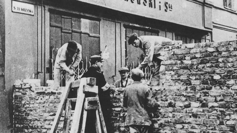 A group of men building a stone wall across a city street Partially obscured.