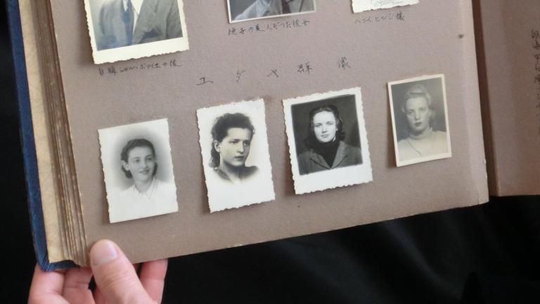 An open photo album contains black-and-white headshots of seven individuals and other annotated photos Partially obscured.