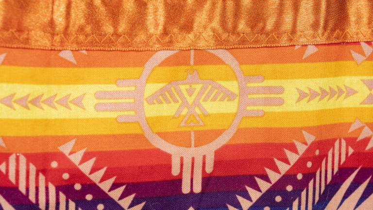 This section of the orange jingle dress shows a thunderbird. Partially obscured.