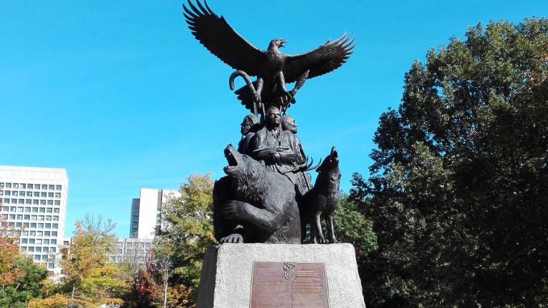 The National Aboriginal Veterans monument, an outdoor statue featuring three Indigenous veterans, a bear, a wolf and an eagle taking flight on top. Partially obscured.
