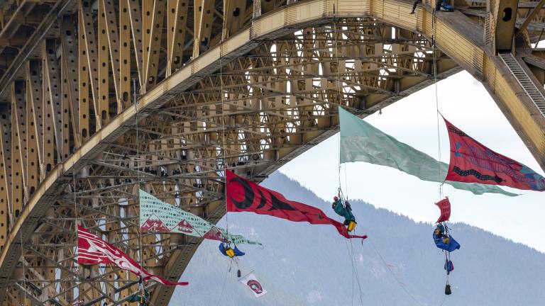 Several large triangular banners hang from the bottom of a large bridge.