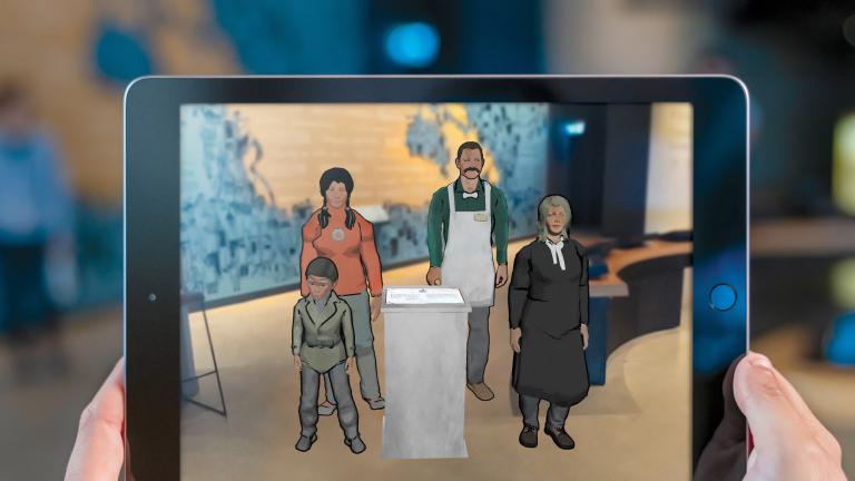 A visitor's hands hold a tablet that carries an image of four animated people including a little boy, a young Indigenous woman, a man wearing an apron and a woman judge. Partially obscured.