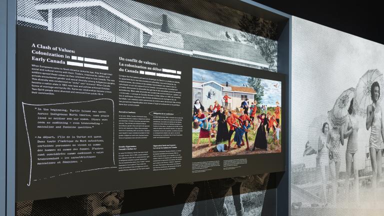 A large exhibit panel on the left features the words “A Clash of Values: Colonization in Early Canada” and a colourful painting. On the right, there is a large black-and-white photograph of people parading in single file in 1940s women’s swimsuits.