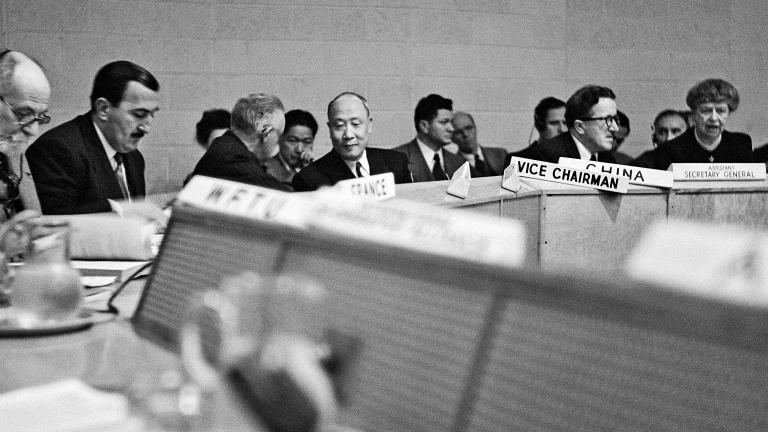 Black and white archival photo of a group of people sitting around a conference table.