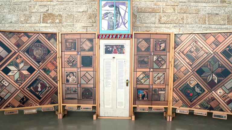 A white door decorated with text and images flanked by vertical wood panels covered in patterns of images.