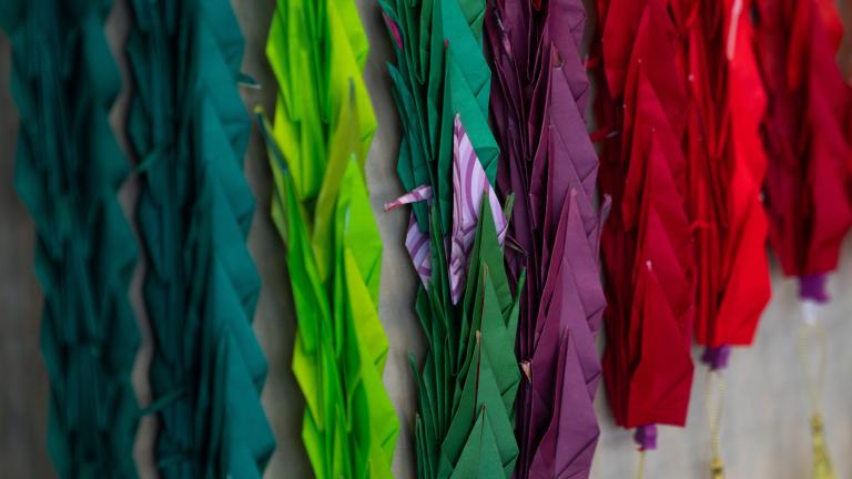 A close-up view of a few of the colourful, folded paper cranes that are part of an installation consisting of one thousand cranes.