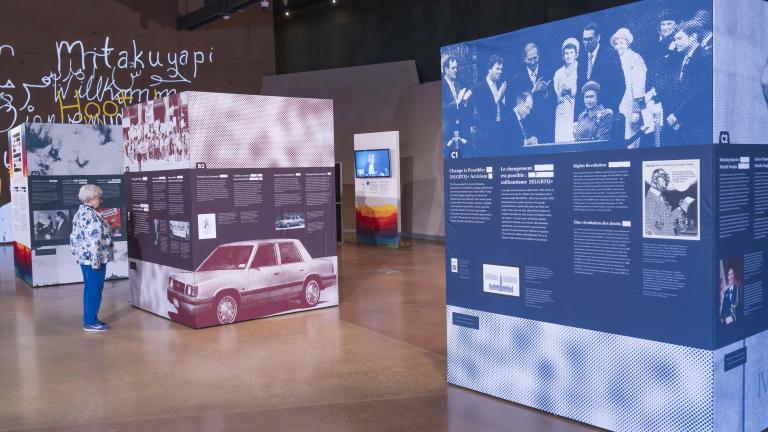 Three large cubes, taller than a person, are covered with images and text. These cubes are the pop-up exhibit Love in a Dangerous Time.