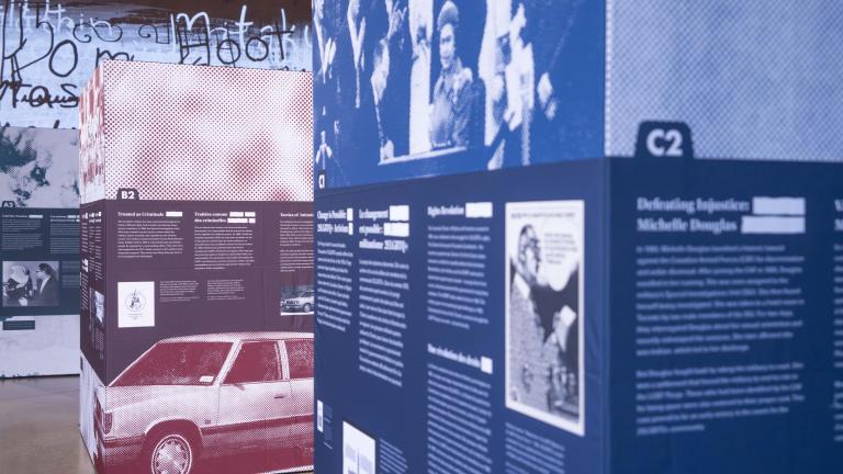 Three large cubes, taller than a person and arranged in a line from front to back, are covered with images and text. These cubes are the pop-up exhibit Love in a Dangerous Time.