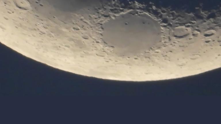 A close-up of a segment of the moon’s surface. Partially obscured.