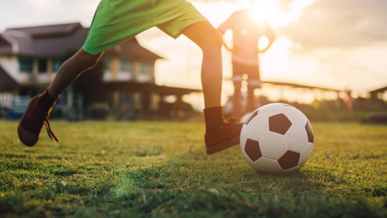 Soccer player on field getting ready to kick the ball. Partially obscured.
