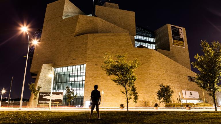  A silhouette of a person faces the exterior north side of the Museum at night (the limestone mountain).