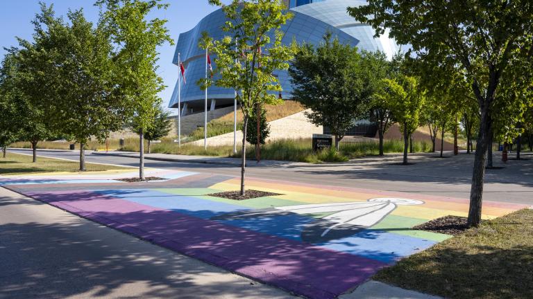 Pride flag pedestrian crosswalk across from the Canadian Museum for Human Rights. Partially obscured.