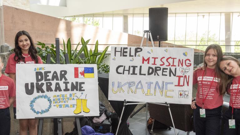 Two posters displayed on easels with a total of groups of two students standing on either side of them. 