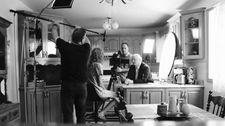 Filming a scene of the movie Fruit Machine, 2 people conversing at a kitchen counter. Partially obscured.