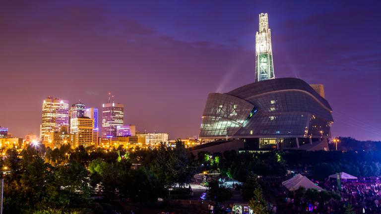 Cityscape view of downtown Winnipeg and the Canadian Museum for Human Rights at nighttime. Partially obscured.