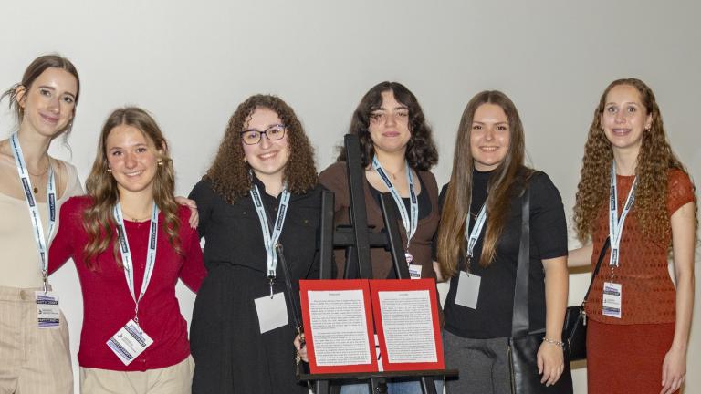 A group of girls stand behind a game of hopscotch. The last few squares have red on them, resembling blood.
