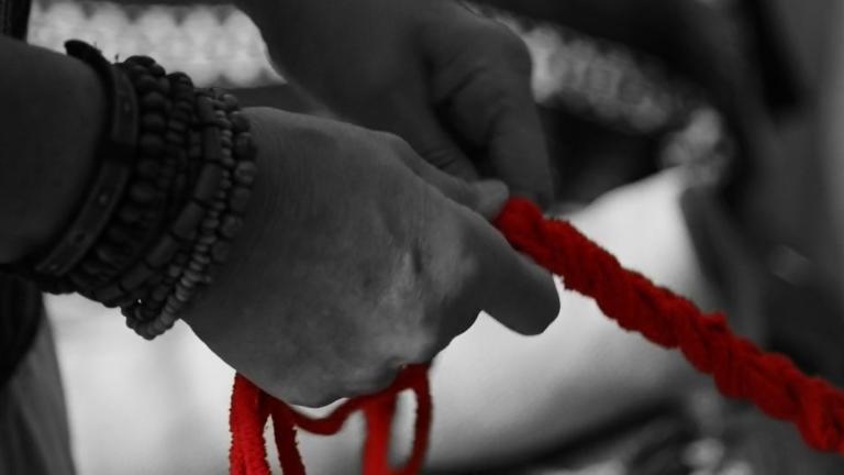 Two hands in black and white hold onto a red rope. Partially obscured.