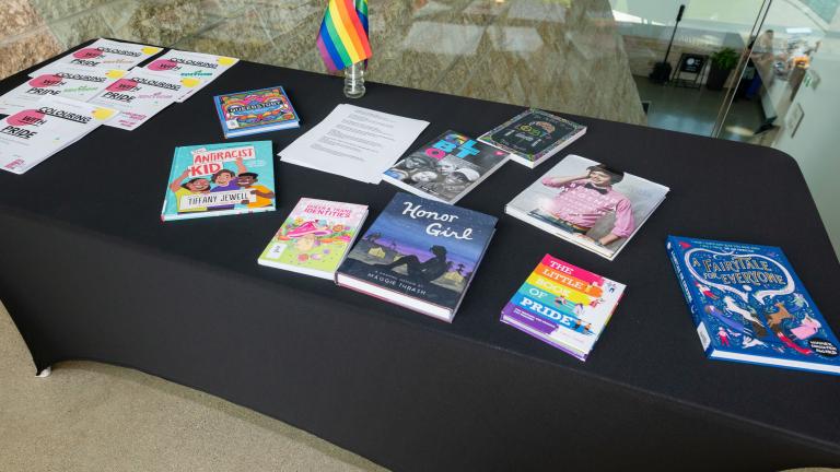 A table with a black tablecloth and colourful books relating to 2SLGBTQI+ Partially obscured.