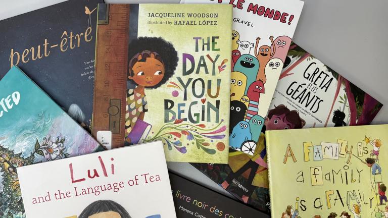 Kids’ books are spread out on a table Partially obscured.