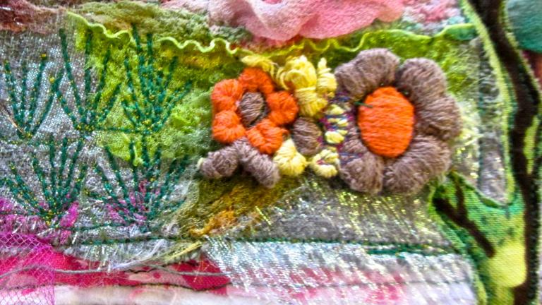 A colourful textile art piece that includes embroidered flowers, branches and greenery mixed with layers of pink, blue and white fabrics. Partially obscured.
