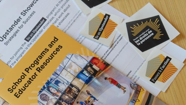 Sheets of paper, booklets and stickers laying on a table. Partially obscured.