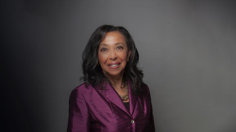 A portrait of a Black woman with long hair wearing a plum-coloured jacket.