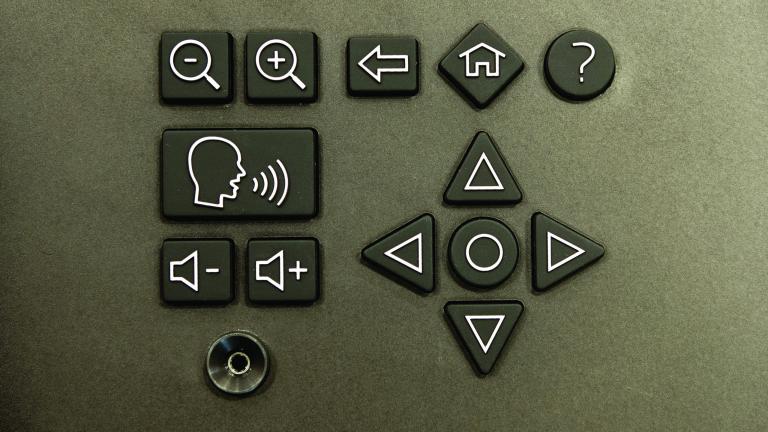 A headphone-style jack and a keypad with symbols indicating volume, magnification and navigation controls.
