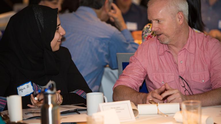 Two people talking at a table. Partially obscured.