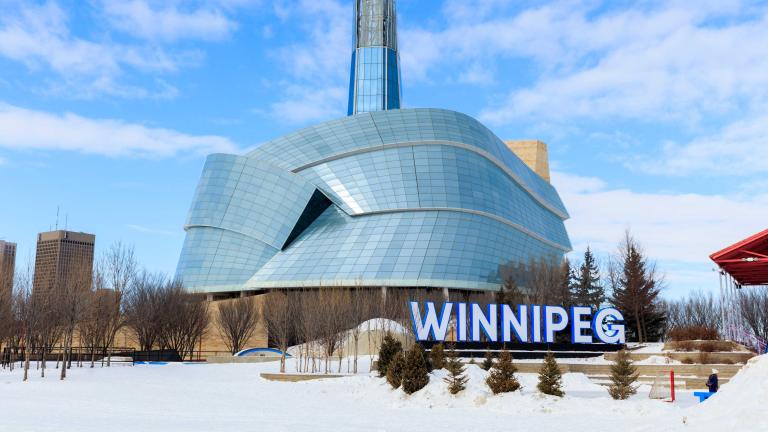 Image of the CMHR in the winter with Winnipeg sign. Partially obscured.