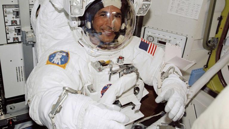 A smiling man in an astronaut suit. Partially obscured.