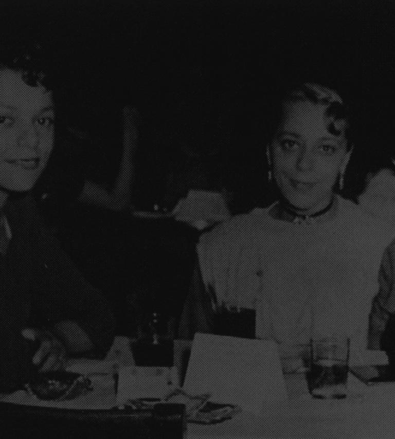 A black and white photo of Viola Desmond (centre) at a club with her sister and brother-in-law (1955). Partially obscured.