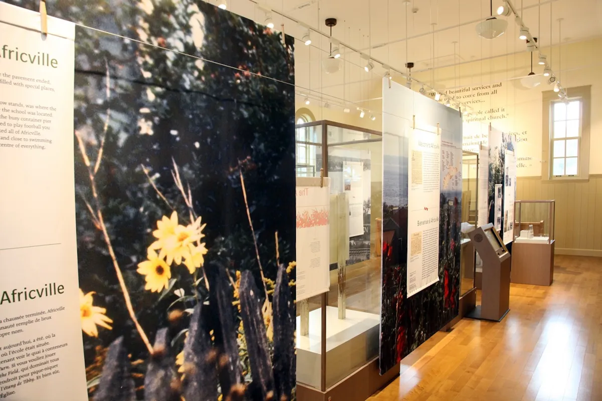 A large room that is filled with glass display cases, text panels in English and French, and large pictures. There are also many tracks of lighting on the ceiling.