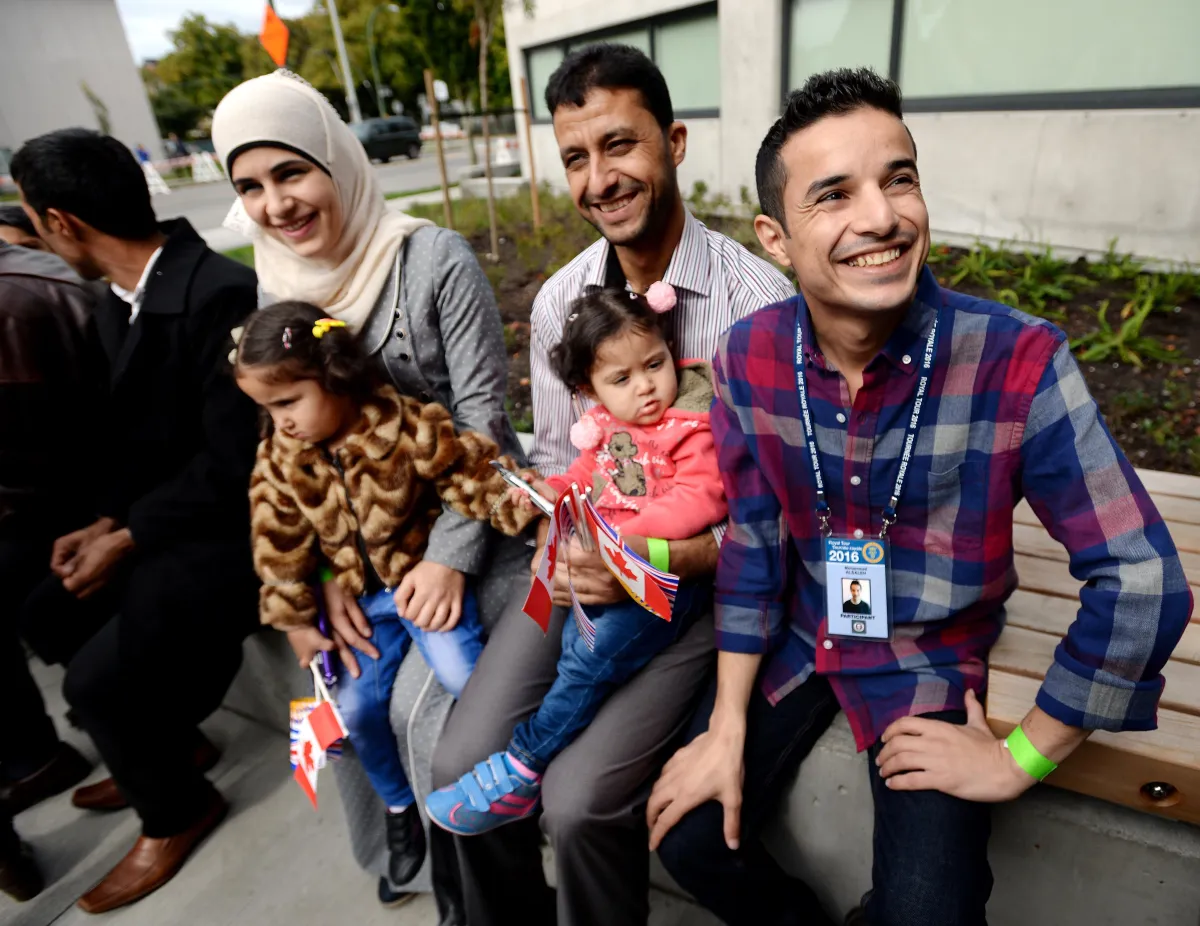 A man sitting with a family of two children; the adults are all smiling.