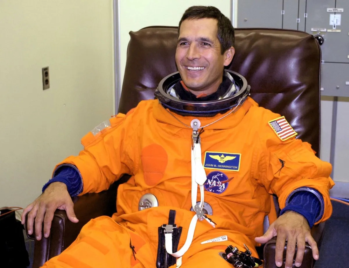 A smiling man in an orange astronaut jumpsuit.