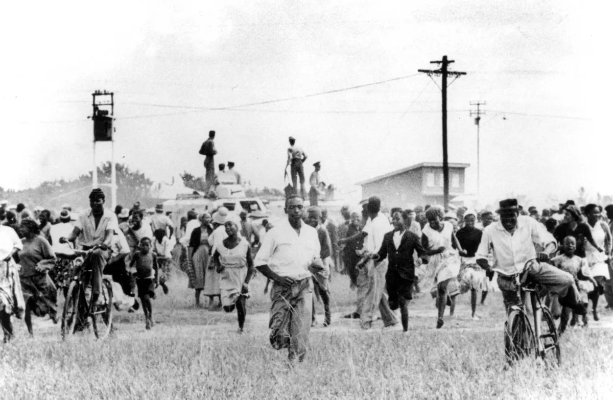 A large crowd of people run, and two people ride bicycles, in the direction of the camera.