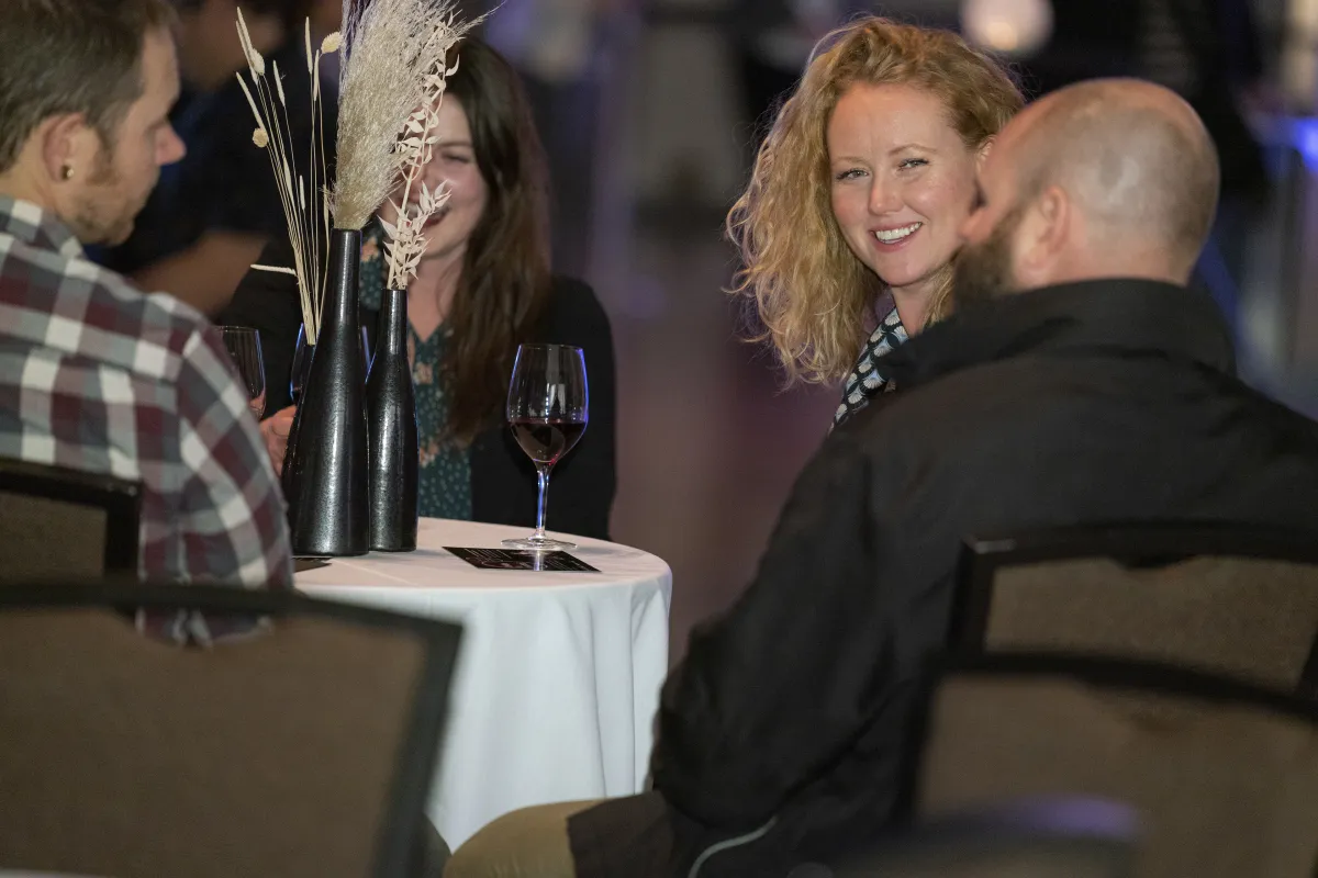 Four smiling people at a table drinking wine.