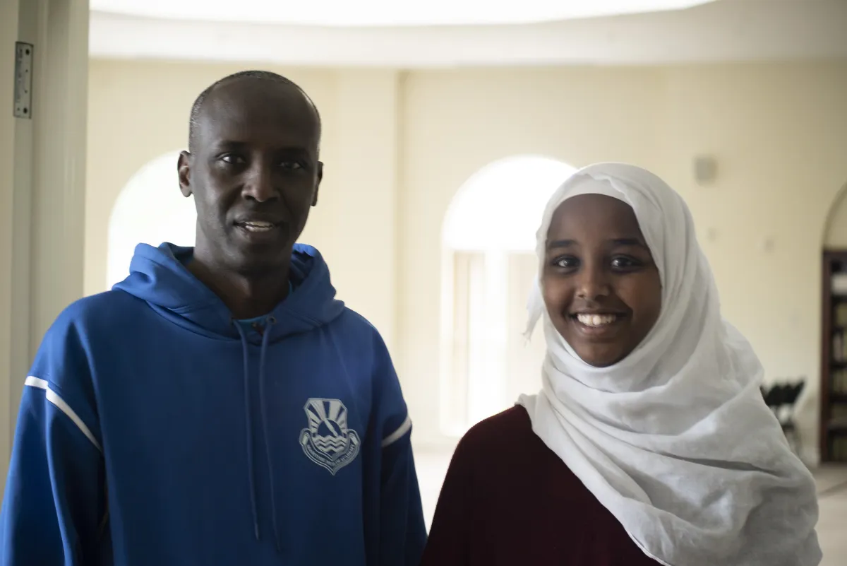 A man stands next to a young woman wearing a headscarf. 