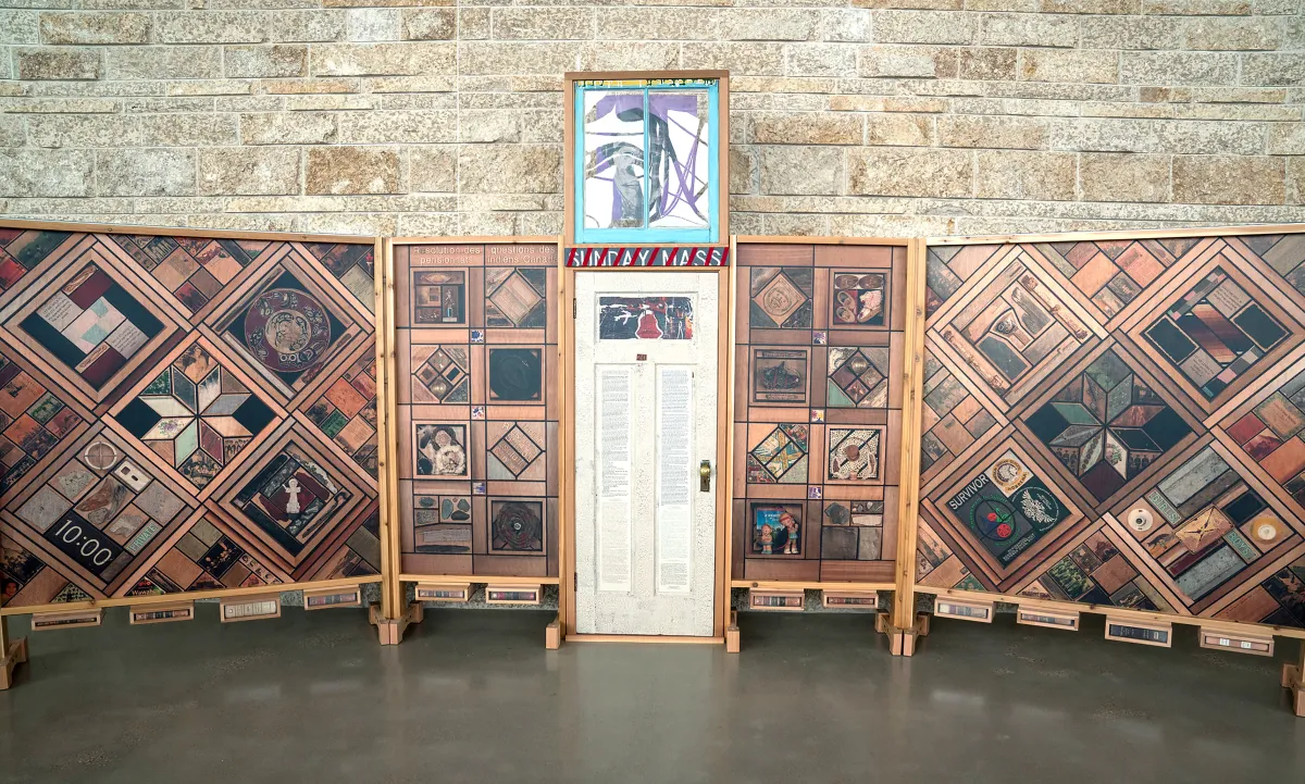 A white door decorated with text and images flanked by vertical wood panels covered in patterns of images.