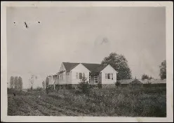 Black-and-white image of a farmhouse in a field