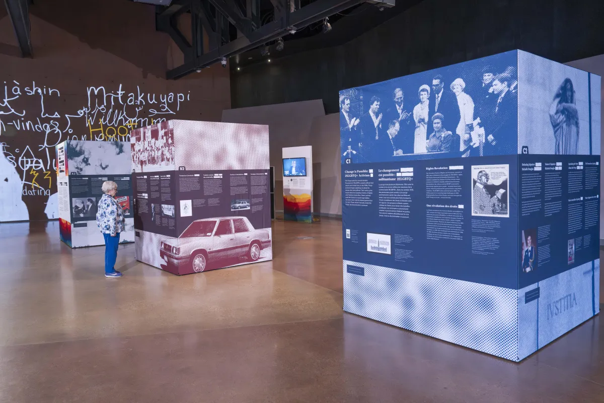 Three large cubes, taller than a person, are covered with images and text. These cubes are the pop-up exhibit Love in a Dangerous Time.