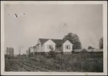 Black-and-white image of a farmhouse in a field