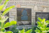 A stone wall with carved decorative script, information panels and a bas-relief portrait of a man above the words “Elzéar Goulet 1836-1870.”